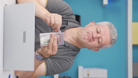 Vertical-video-of-Home-office-worker-man-making-money-and-feeling-happy.